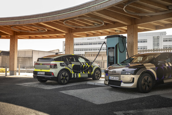 Outdoor shot of two Audi A2 e-tron vehicles at a charging station.